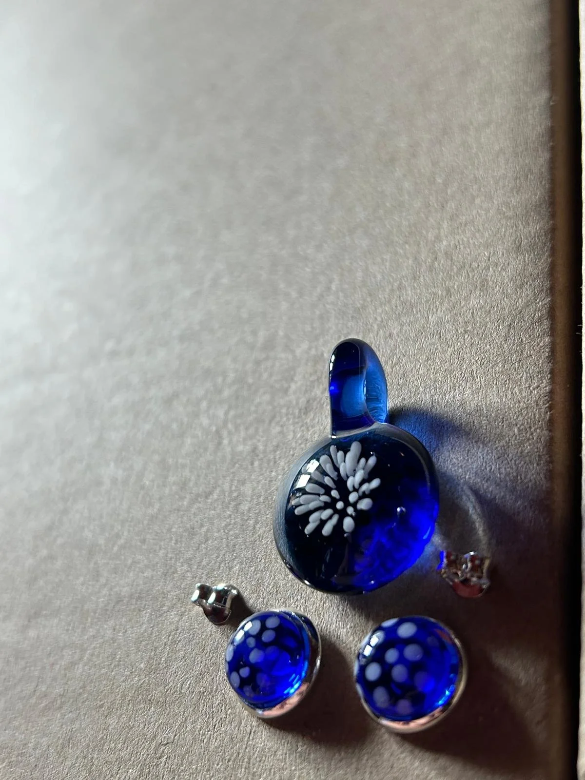 Handgefertigtes Schmuckset aus blauem Borosilikatglas mit weißem Blütenmuster und passenden Ohrsteckern