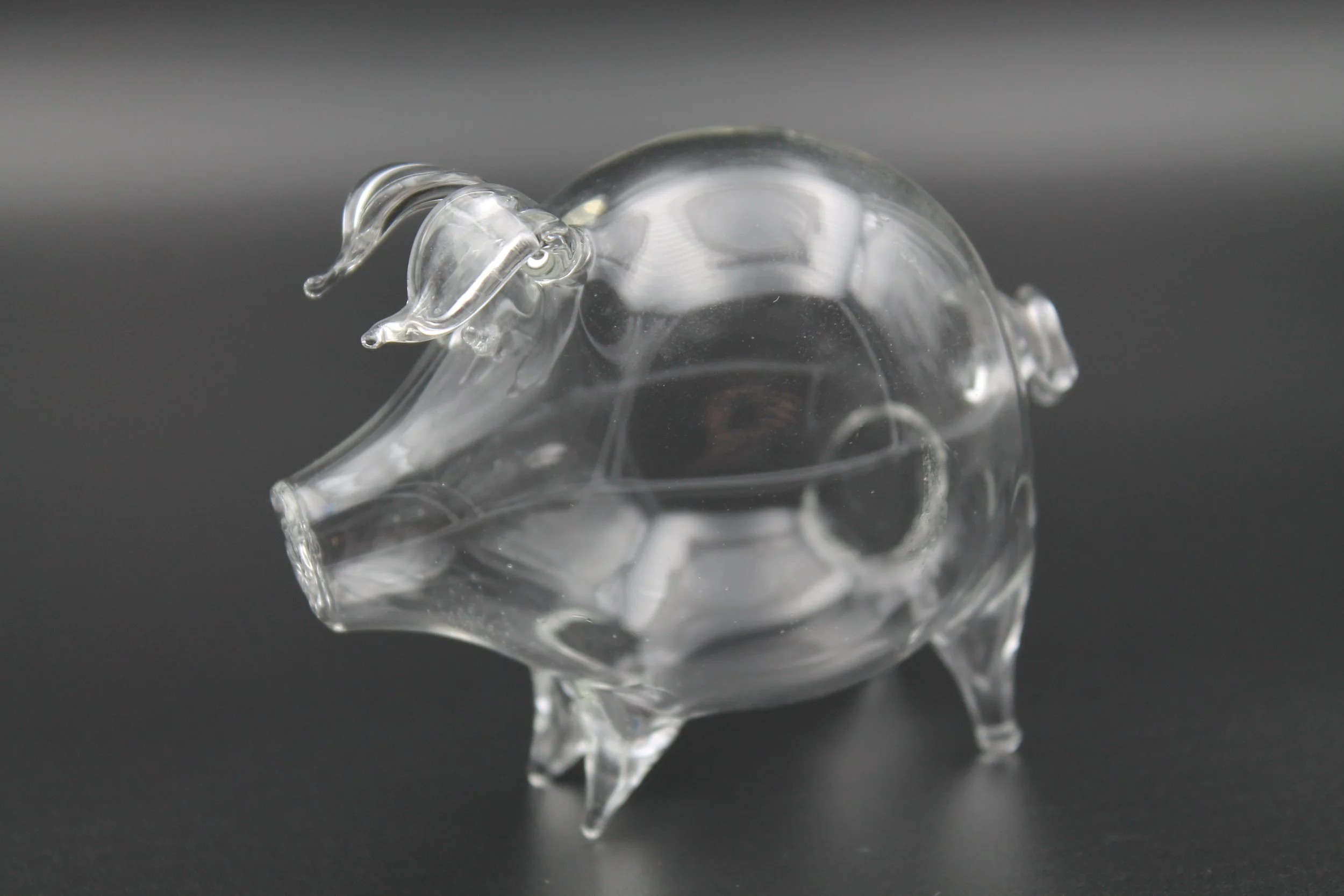 Handgefertigtes Schwein aus klarem Borosilikatglas auf dunklem Hintergrund