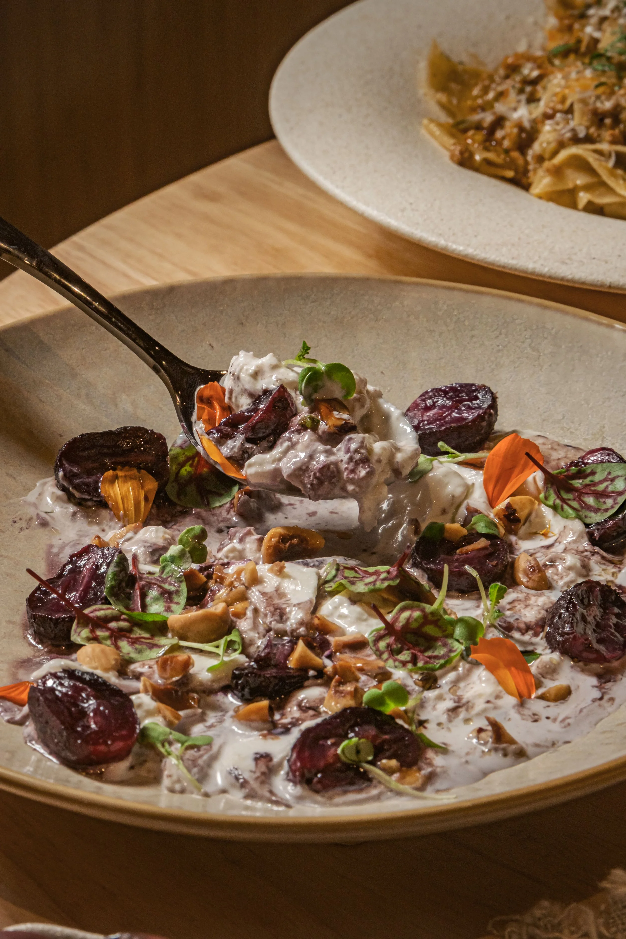 A bowl of salad with beets, microgreens, and chopped nuts, topped with a creamy dressing.