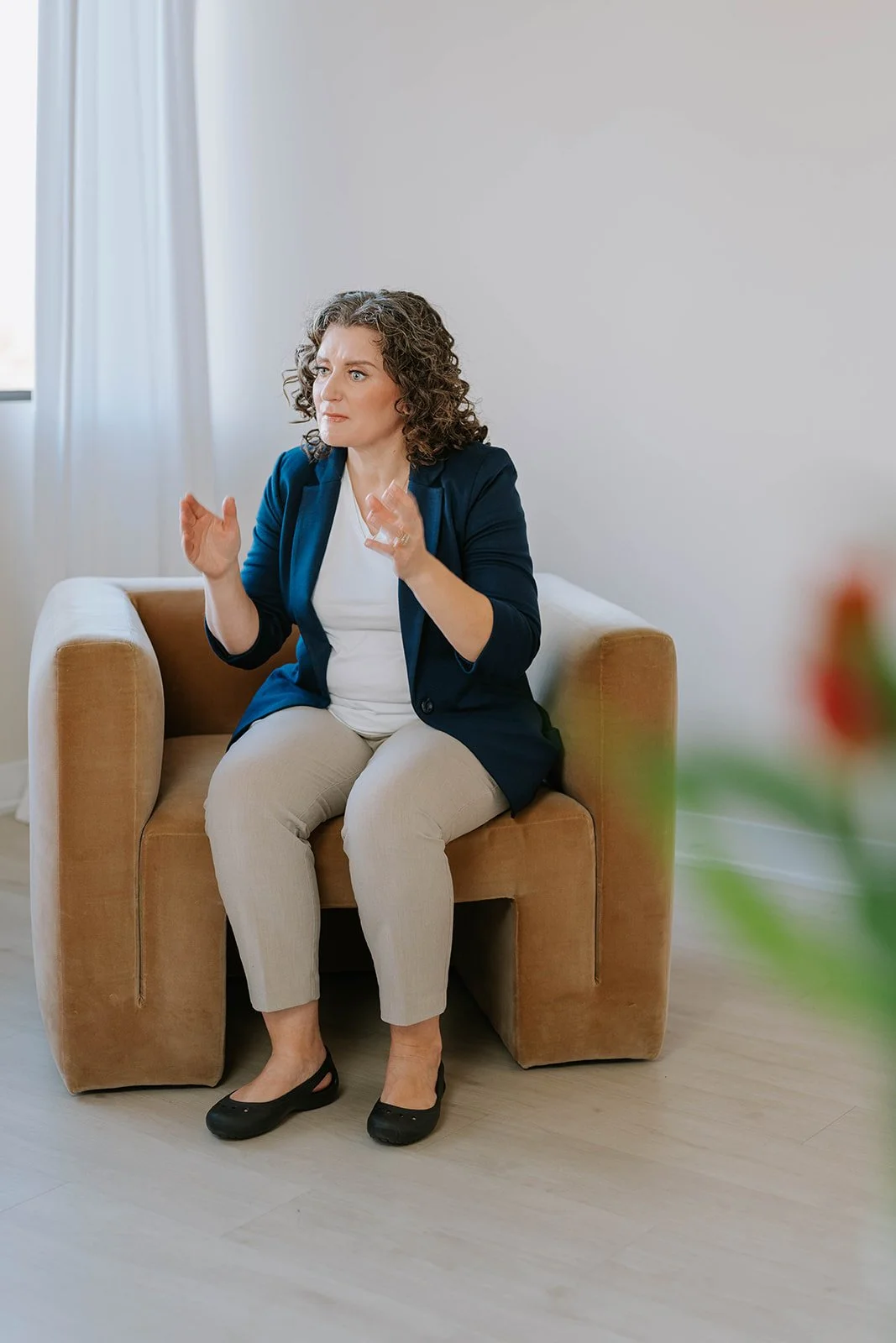 Marie-Claire McKelvey sharing her insights while seated in a chair, reflecting her passion for advocacy, resilience, and meaningful conversation.