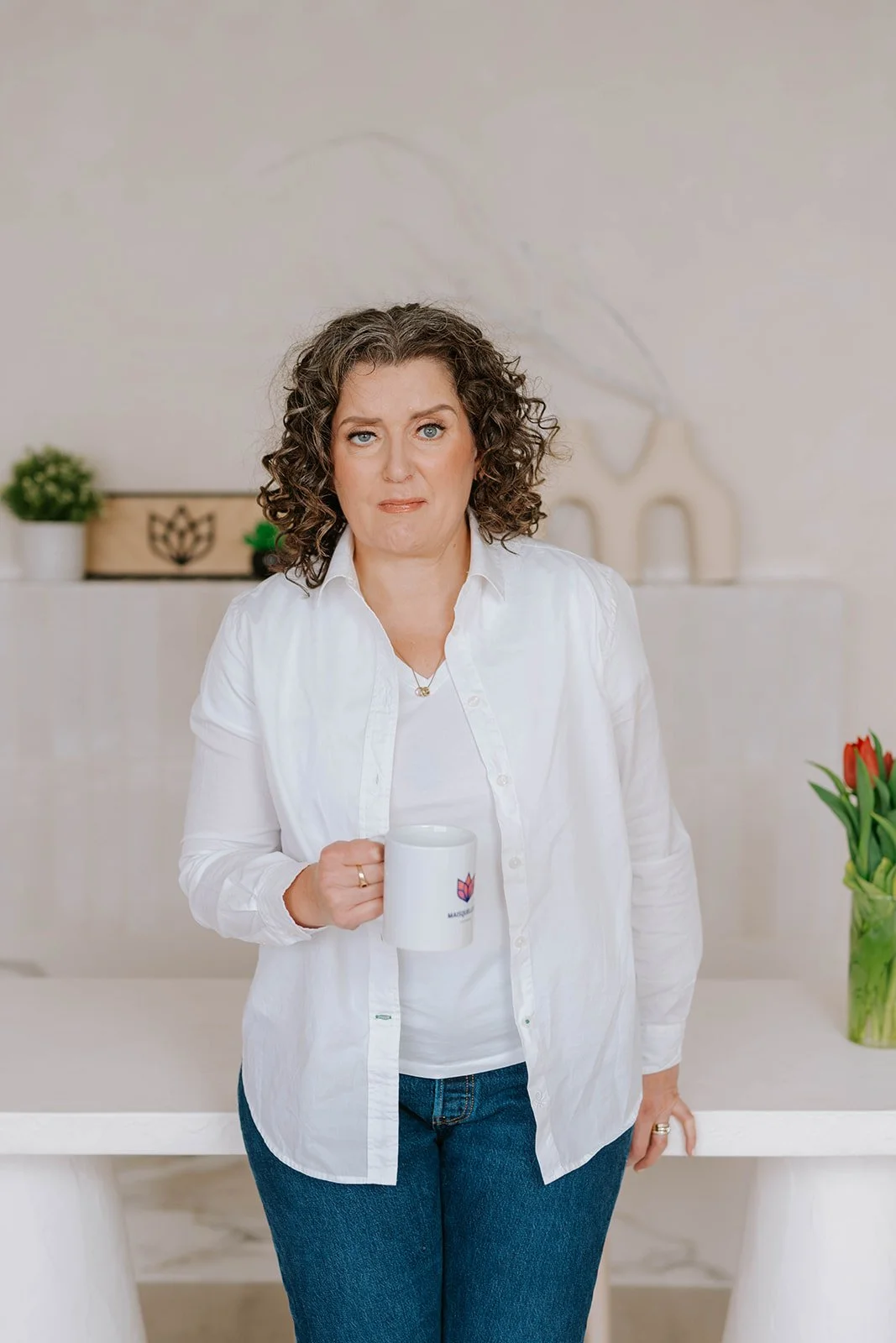 Marie-Claire McKelvey standing with a Mais Quelle Vie Solutions coffee mug, reflecting on resilience, writing, and advocacy.