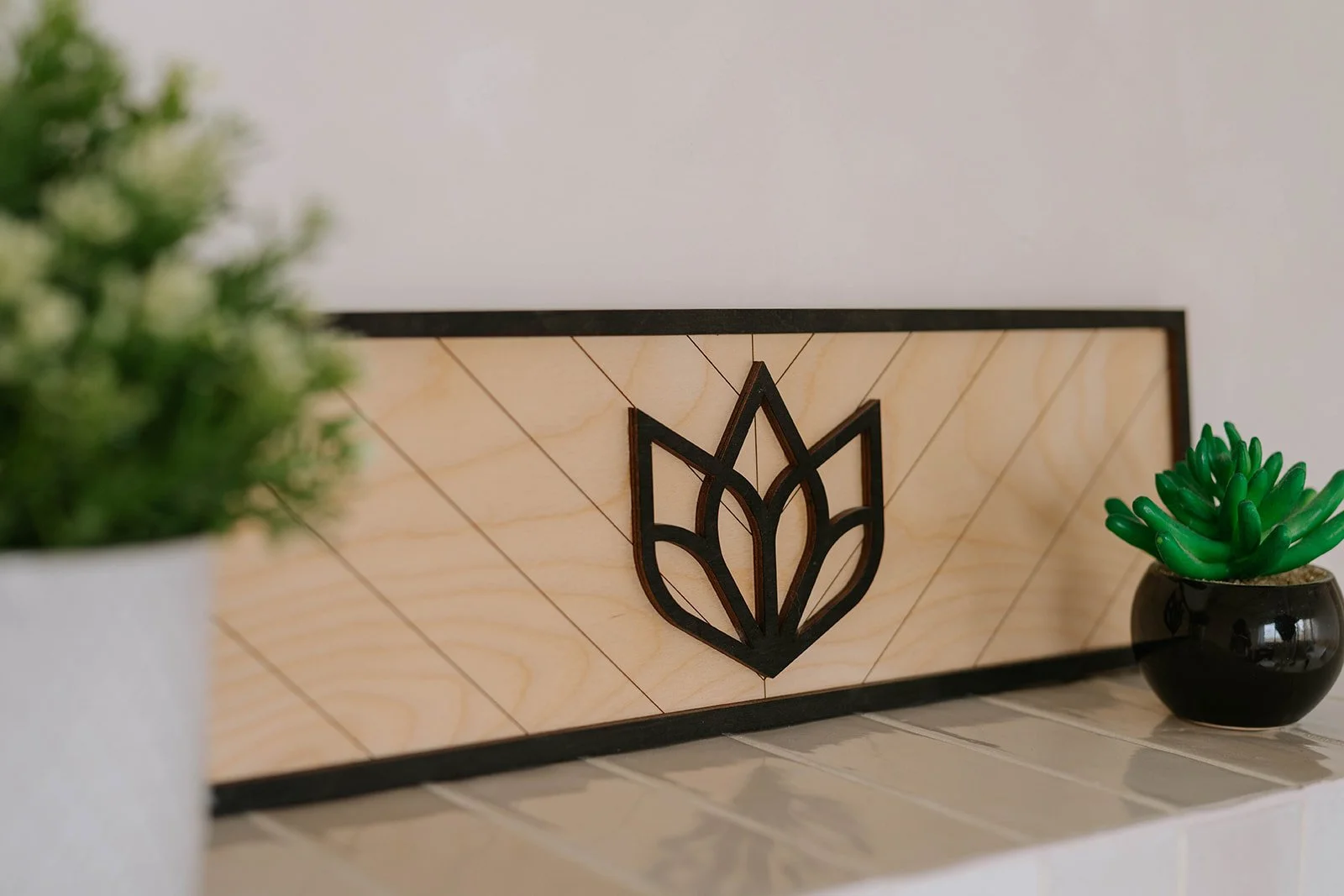Mais Quelle Vie Solutions logo displayed on a handcrafted wooden sign with decorative plants.