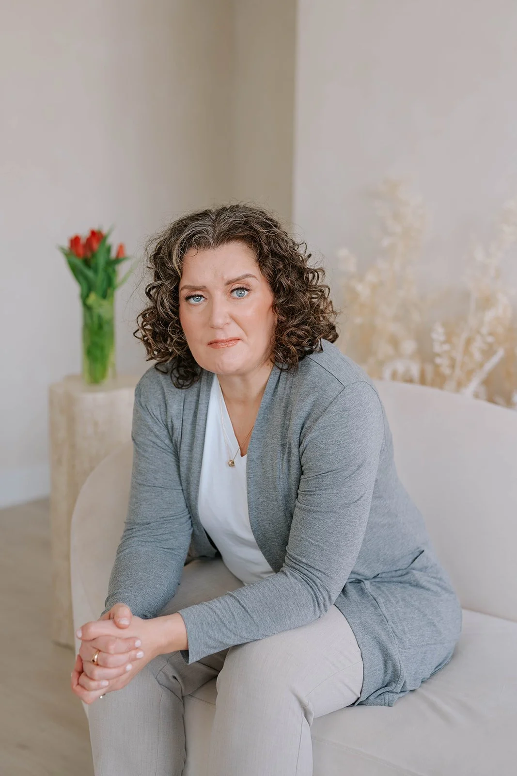 Marie-Claire McKelvey seated on a sofa with red tulips in the background, reflecting on resilience and hope.