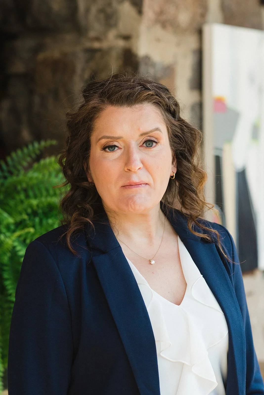 Professional portrait of Marie-Claire McKelvey, author and social work student, standing in front of artwork with a calm and confident expression.