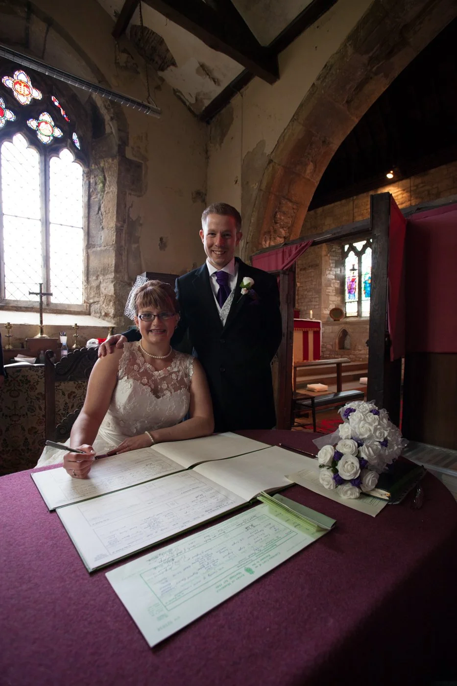 A bride and groom at a wedding signing register inside a historic church.