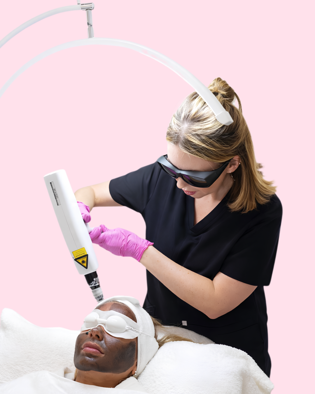 Cosmetologist using laser skin treatment device on a patient lying down with eye protection, in a medical spa setting.