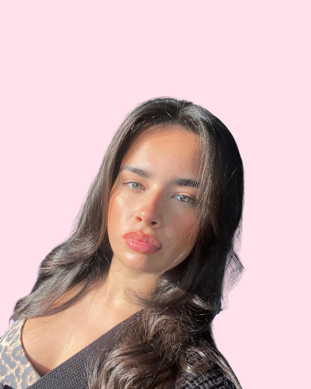 Close-up of a woman with long dark hair, light skin, and blue eyes, against a pink background.