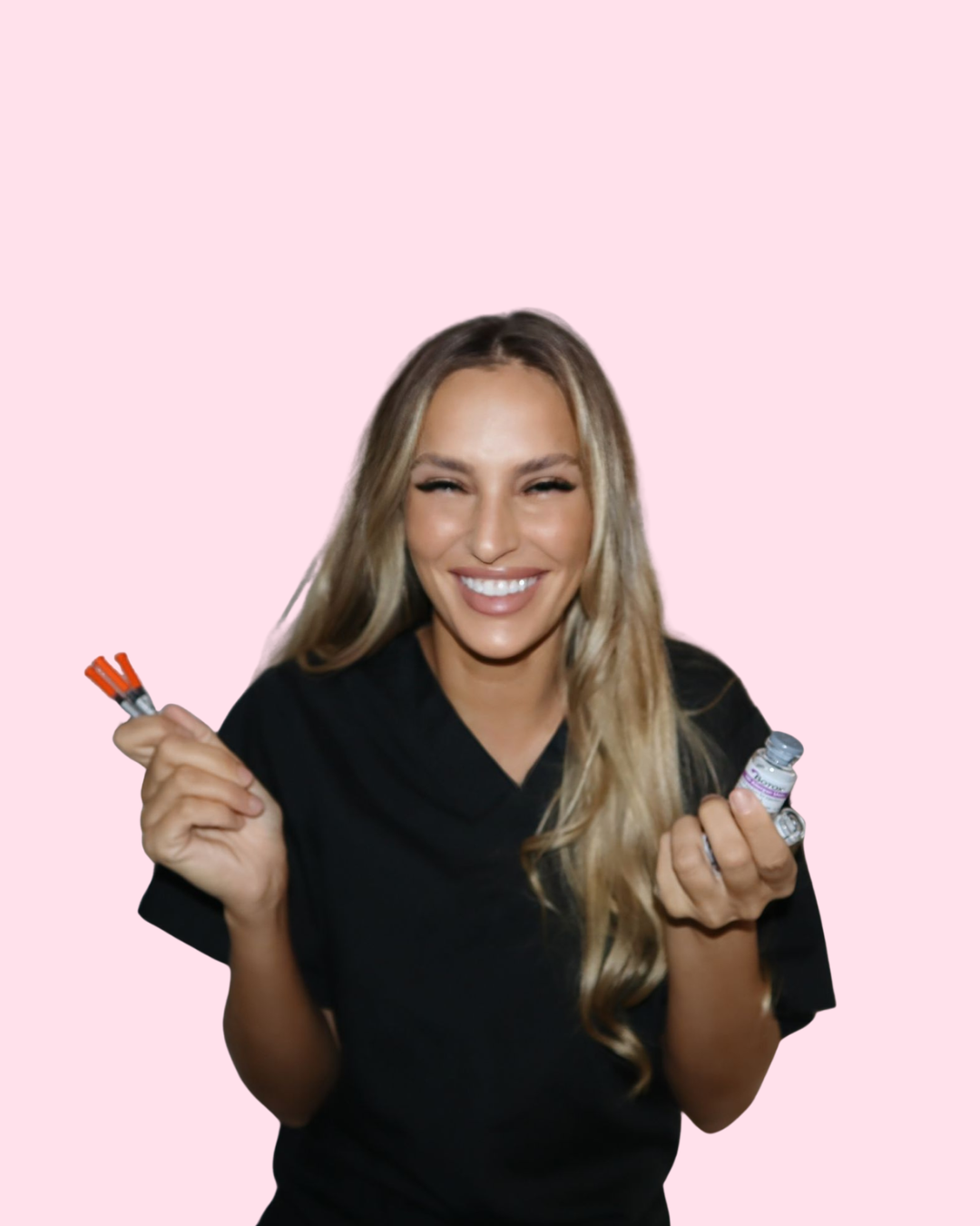 A smiling woman with long blonde hair holding a small bottle and a bundle of red syringes in front of a pink background.