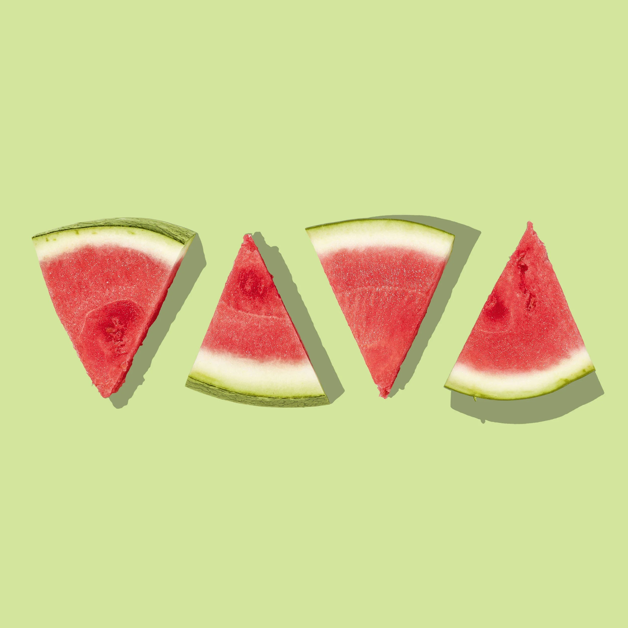 Multiple slices of watermelon on a light green background.