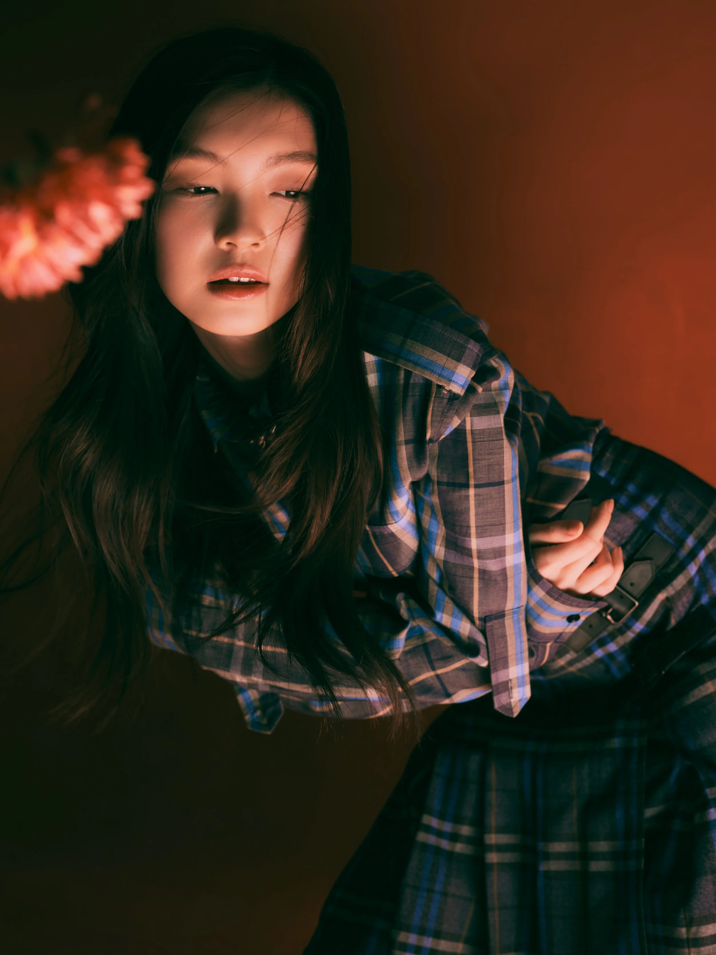 Yoyo Tse, A young woman with long dark hair, wearing a plaid shirt, is sitting against a plain background with soft lighting. Her eyes are slightly closed, and her lips are parted, creating a relaxed, intimate mood.