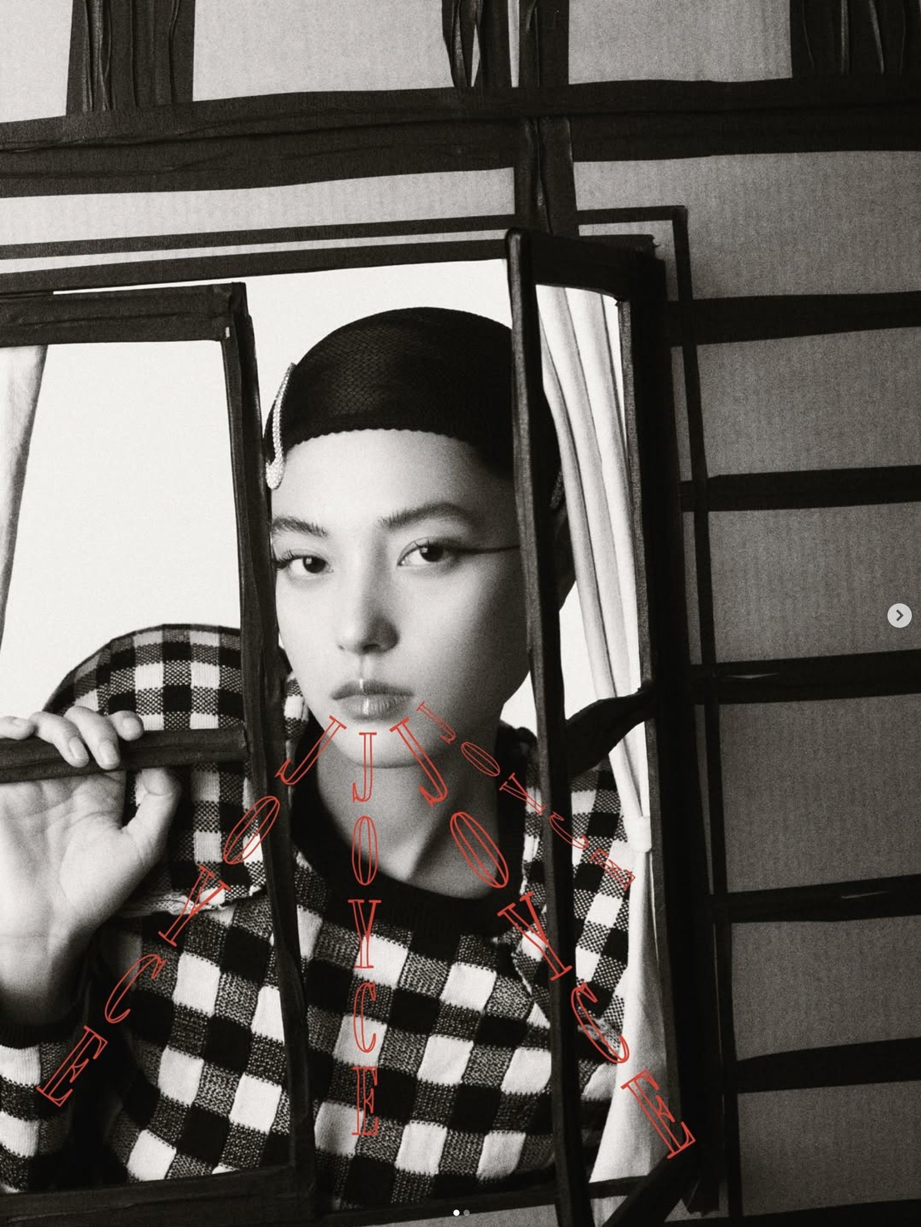 JOYCE Hong Kong, A black and white photo of a woman wearing a checkered shirt and baseball cap, partially visible behind a chair and metal frame structures with red script text overlaying the image.