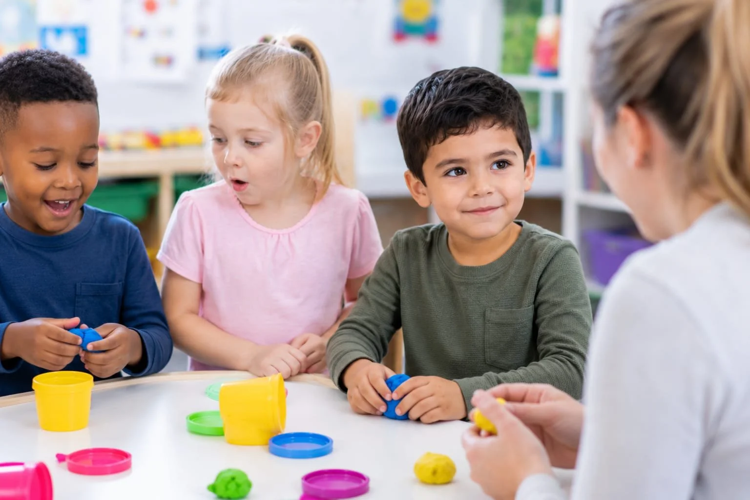 Three young children playing with Play-Doh at a classroom table, while a woman guides them.