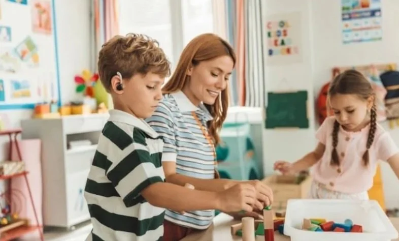 Teacher and children engaging with educational toys in a classroom.