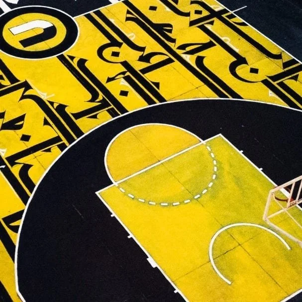 A basketball court with yellow and black colors, showing part of the court and a basketball hoop.