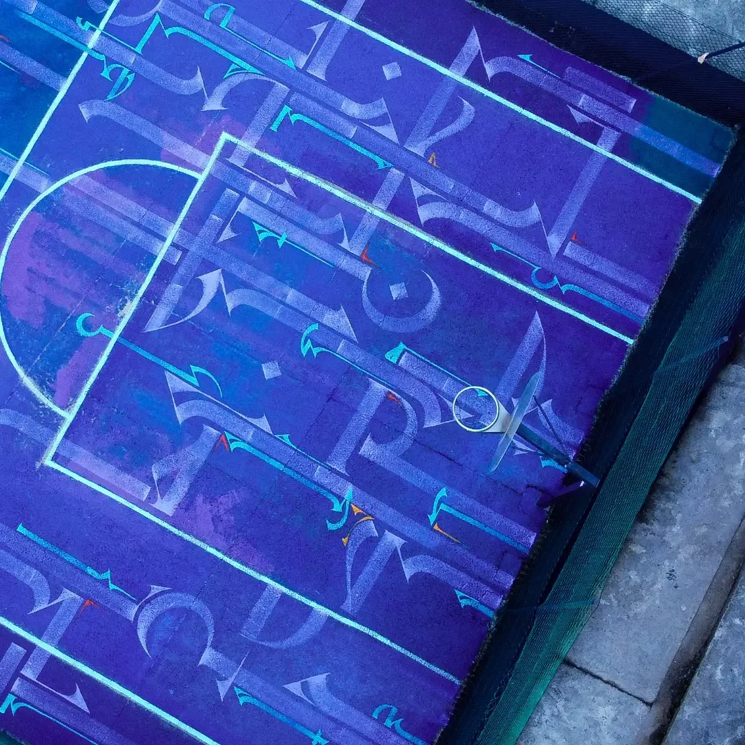 An LED-lit mini soccer field with a ball and goal, illuminated under blacklight with neon blue and purple markings.