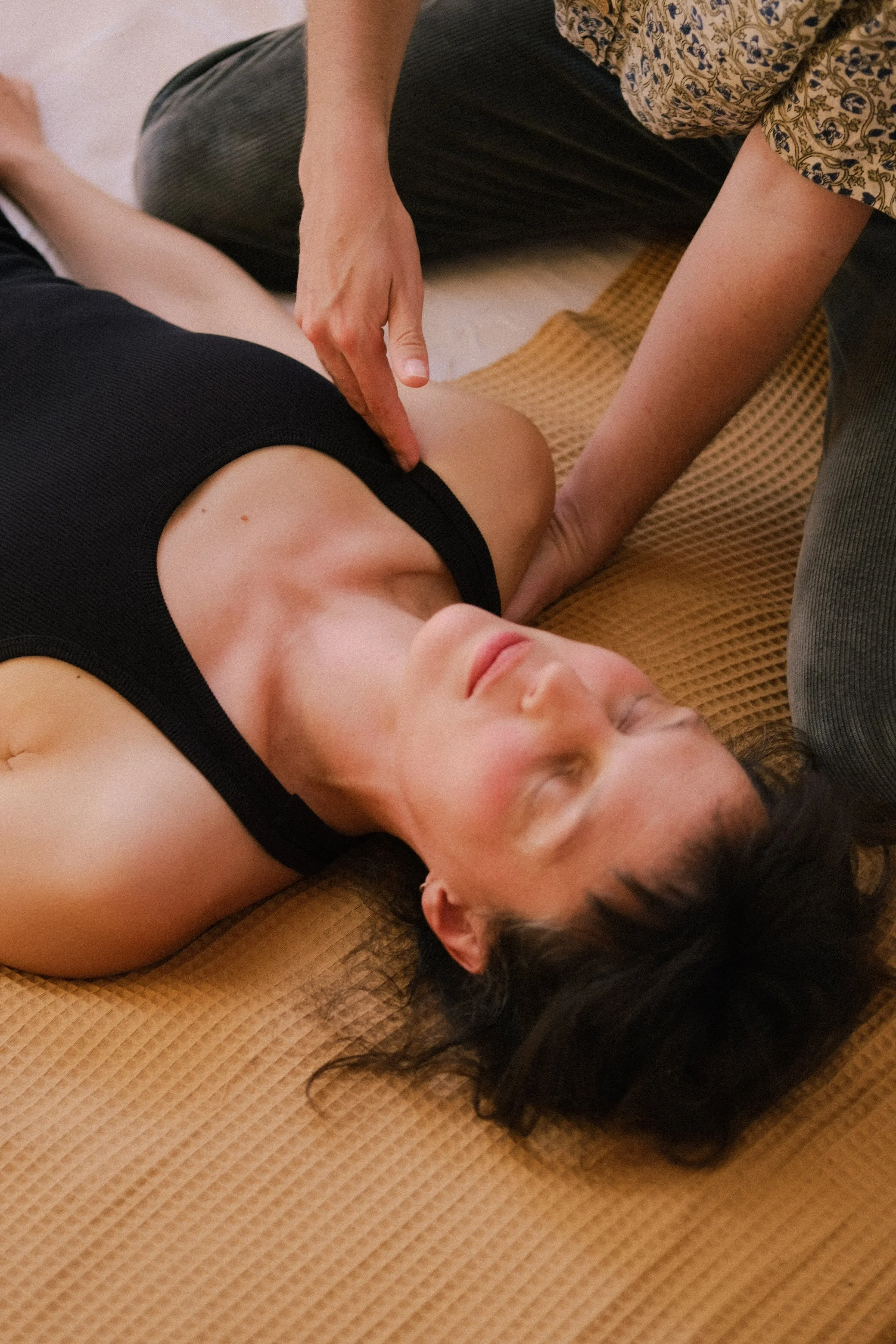 Une femme allongée sur un tapis, recevant une réanimation cardio-respiratoire de la part d'une autre personne.