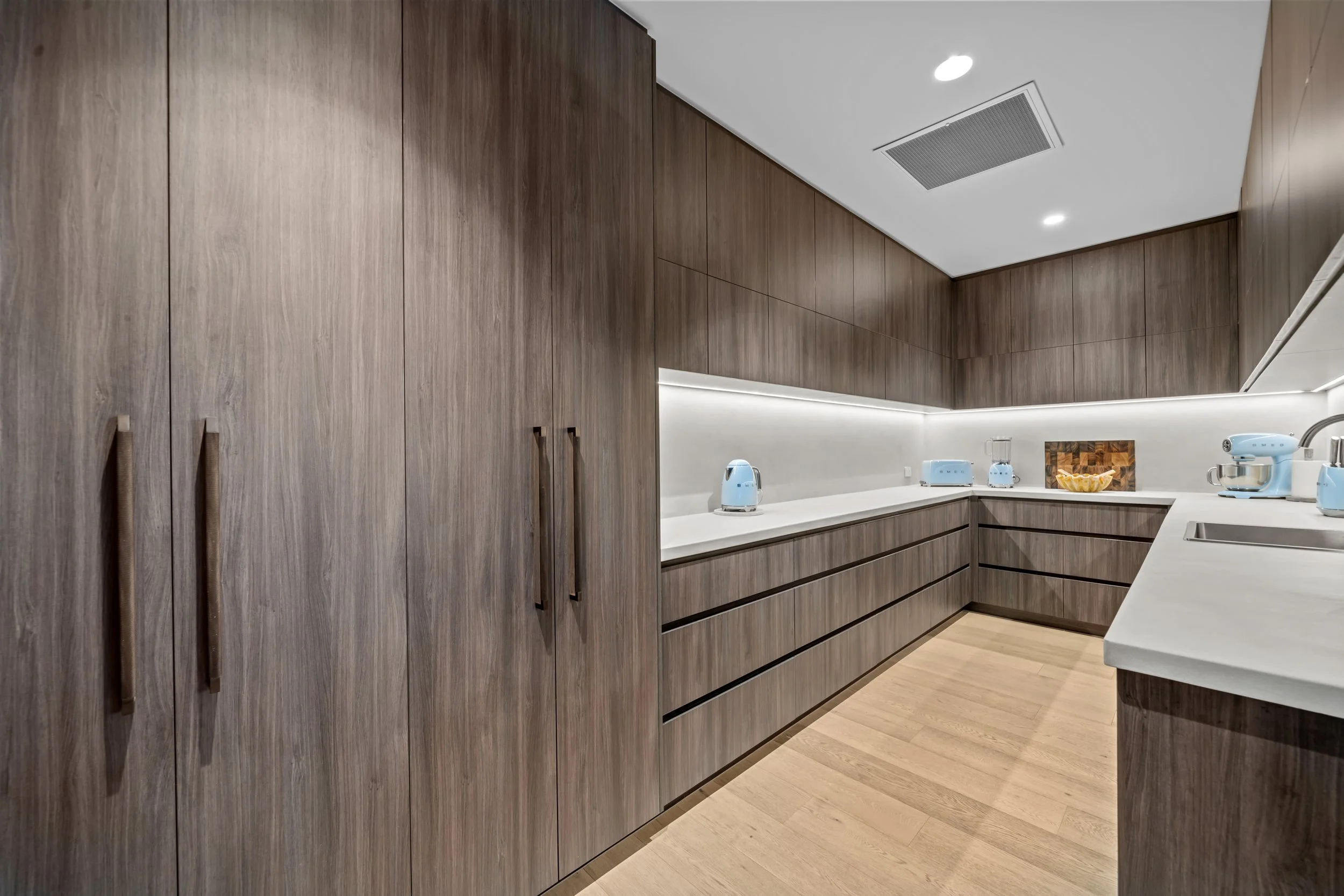 Butler's pantry with dark timber cabinetry and integrated appliances.