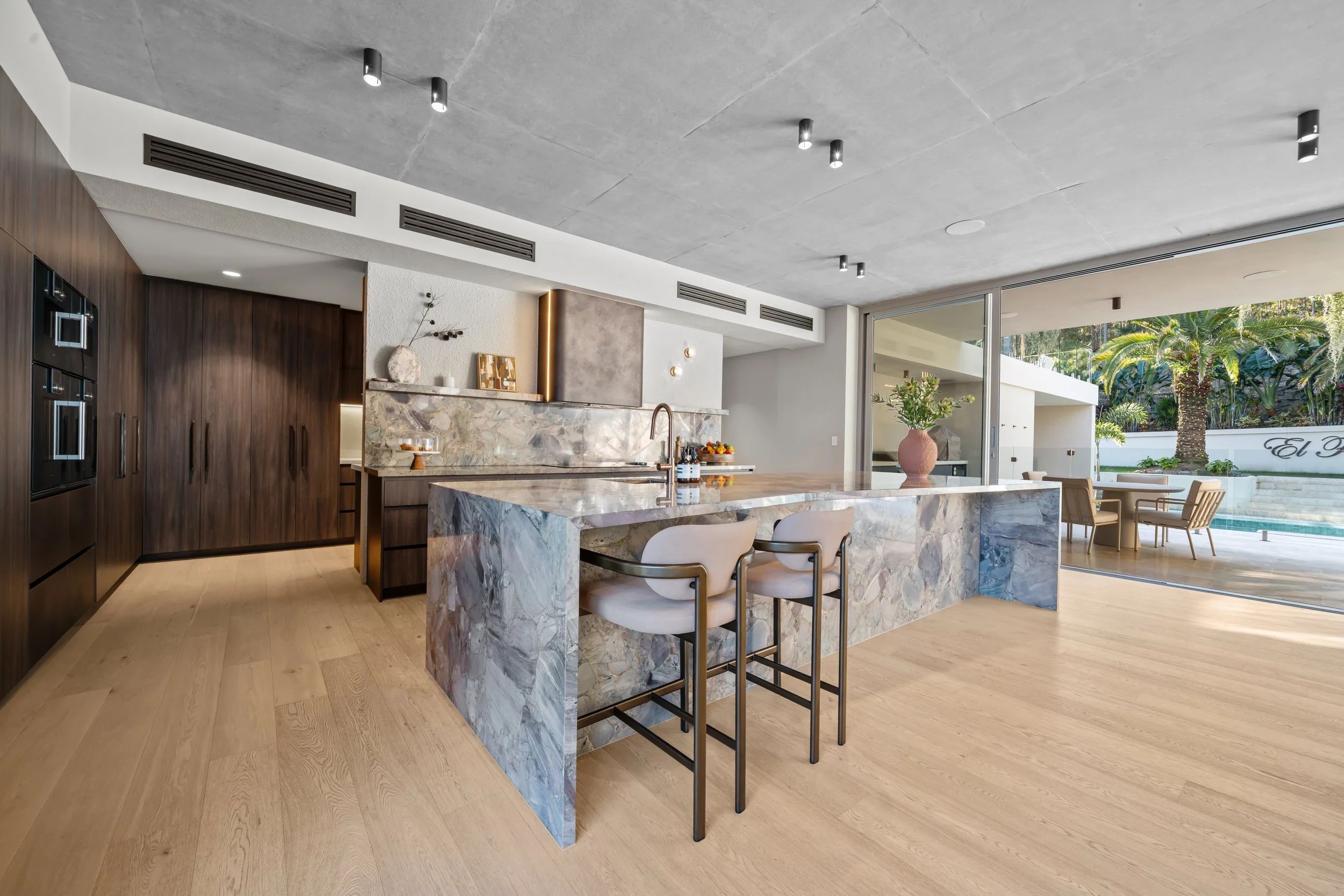Kitchen at Stella Place with dark timber cabinetry and a large stone island with bar seating.