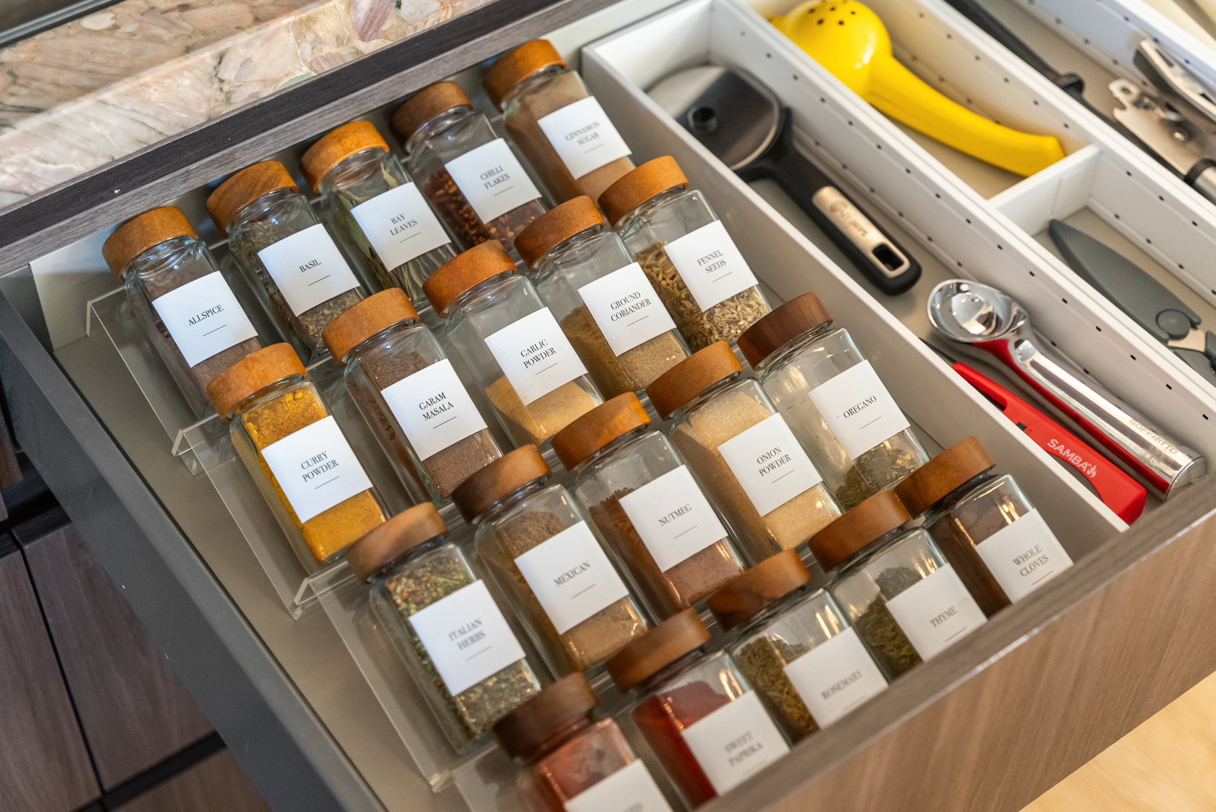 Full spice drawer with labelled jars organised in rows.