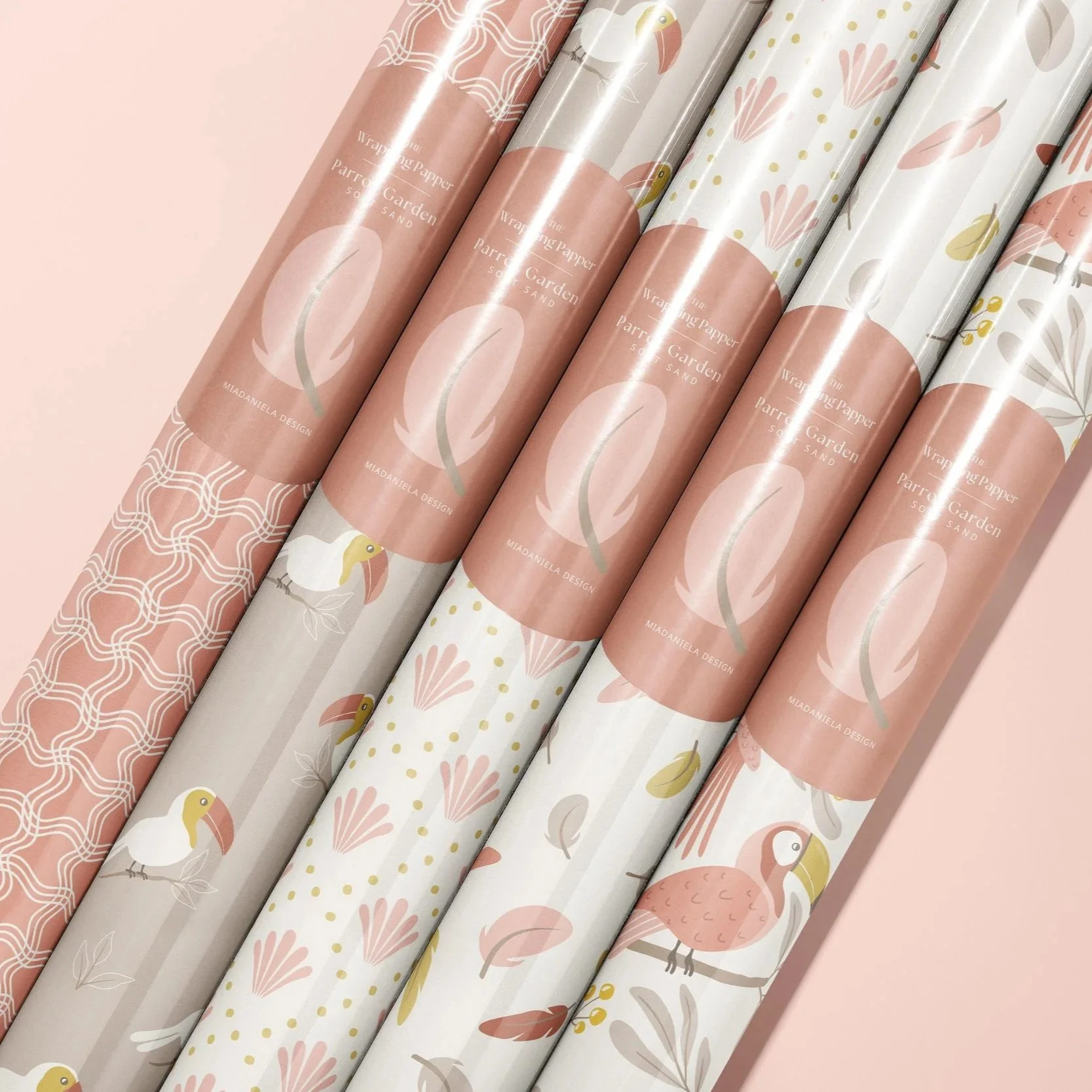 Gift wrap mockup showcasing coordinated botanical and tropical patterns from the Parrot Garden Soft Sand colorway.