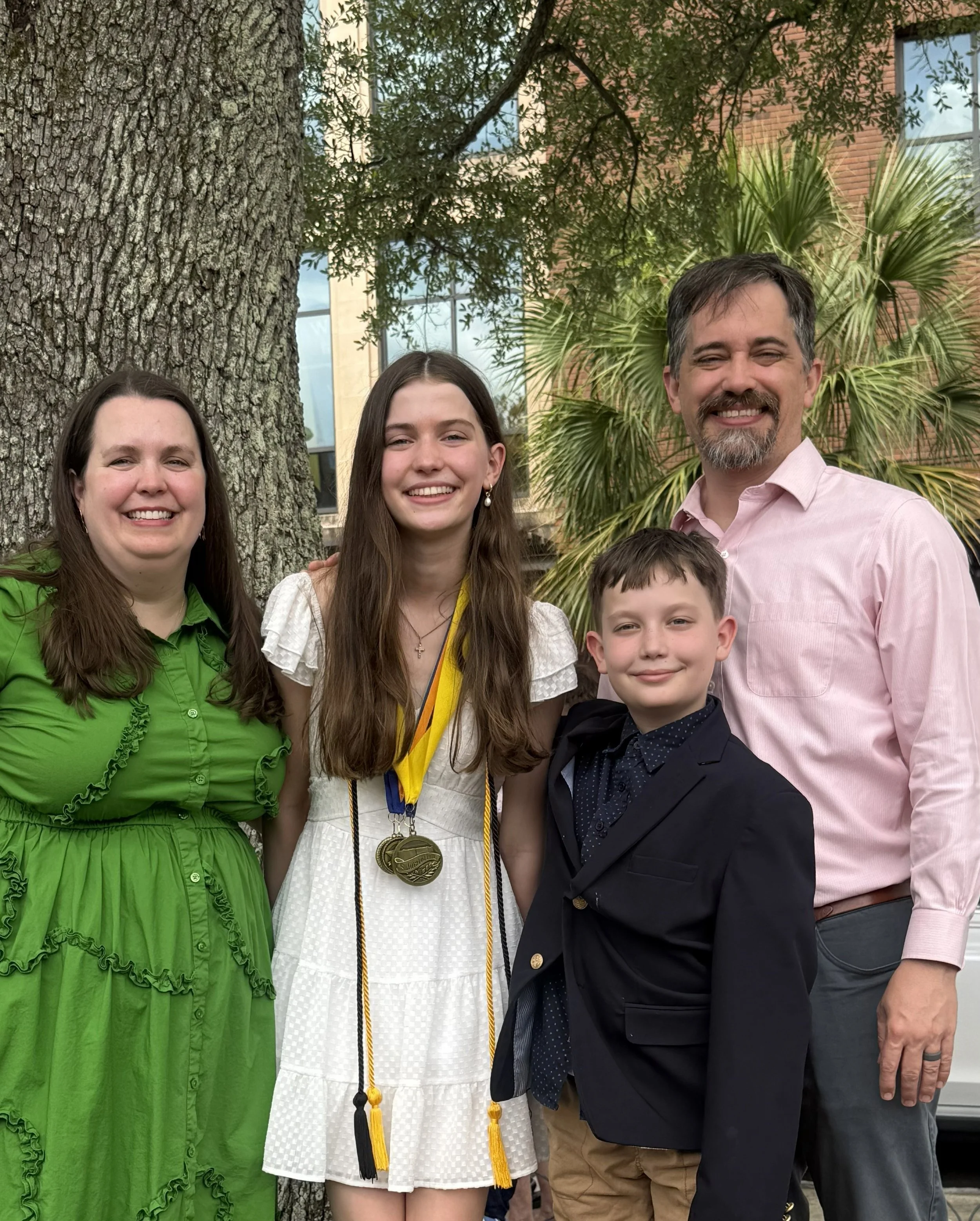 circular picture of Bennett family from left to right: Nathalie in green dress, daughter with 8th grade promotion medals, son in navy suit jacket, and Joseph in light pink button down shirt