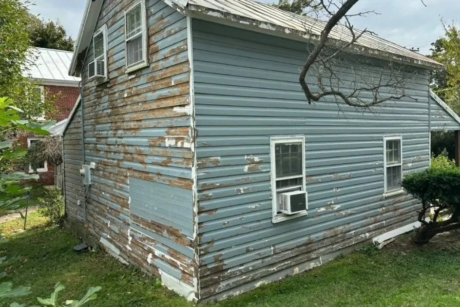 Before: peeling blue-gray paint and exposed wood on the rear gable and side siding.