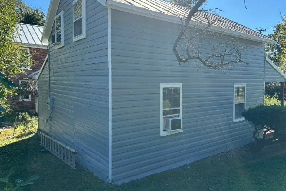 After: a consistent blue-gray finish across the siding with contrasting white window and roofline trim.