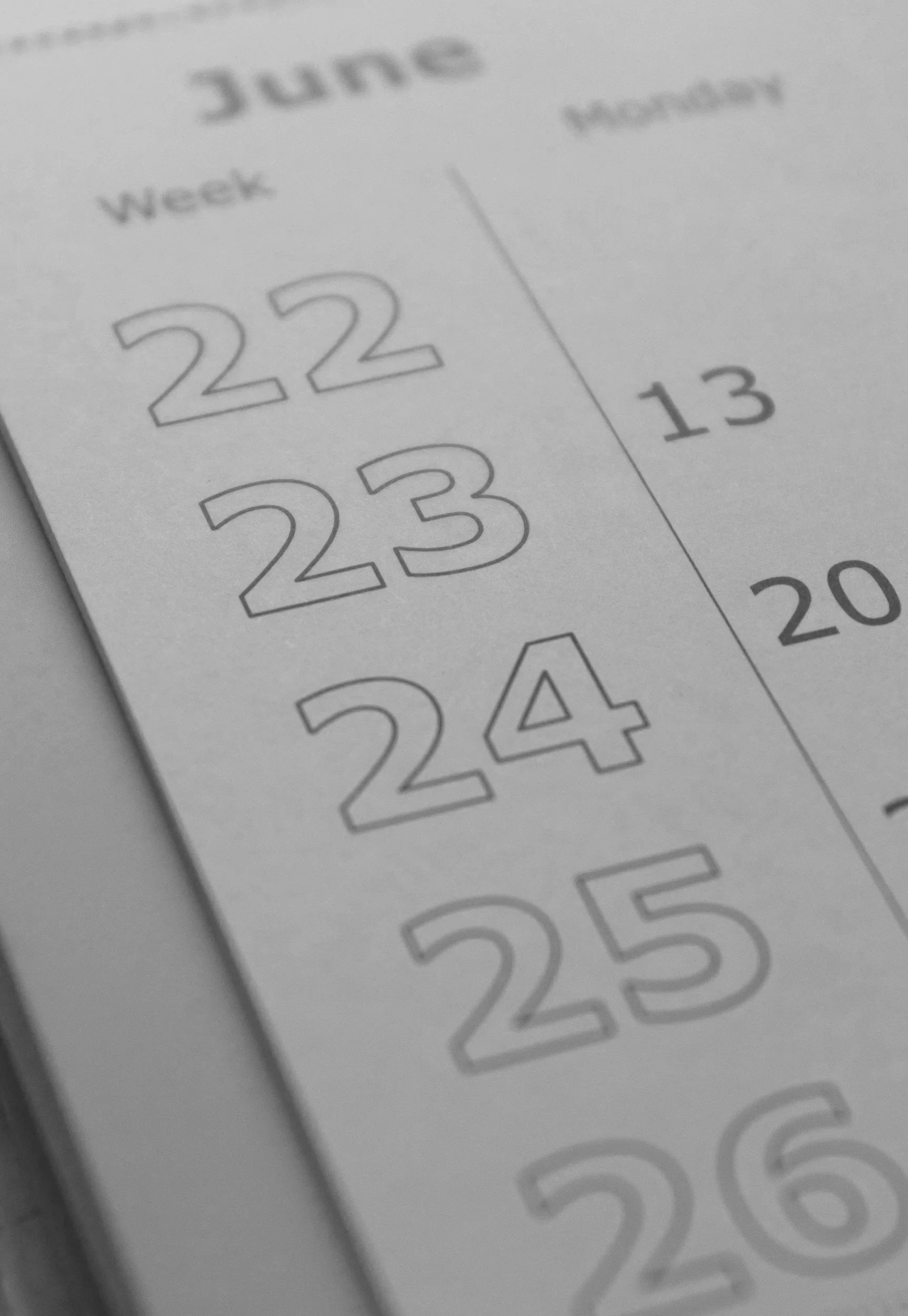 Close-up of a printed daily calendar page showing dates including the 22nd, 23rd, 24th, and 25th, with handwritten notes on some dates.