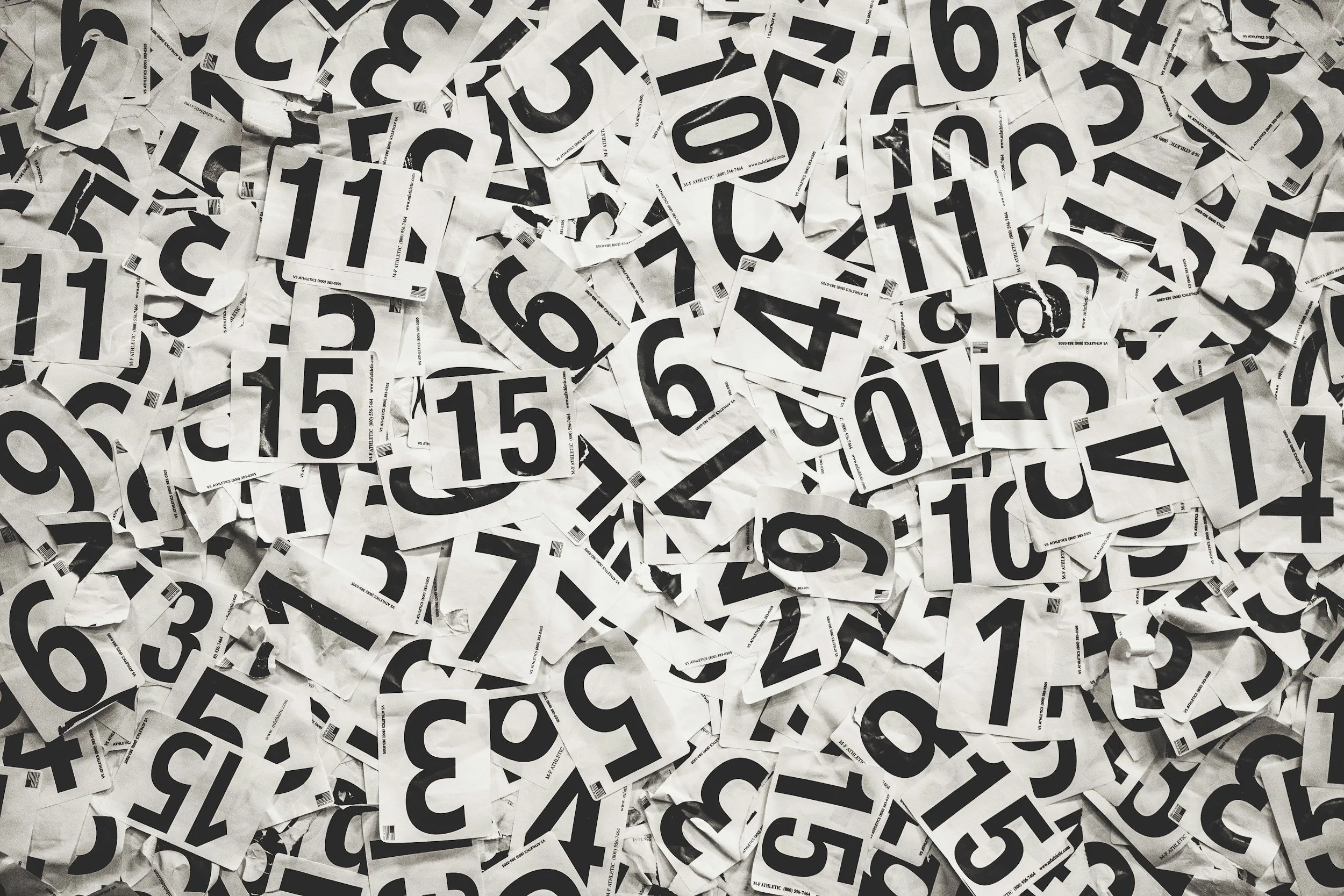 A large pile of torn paper lottery tickets with black numbers on a white background.