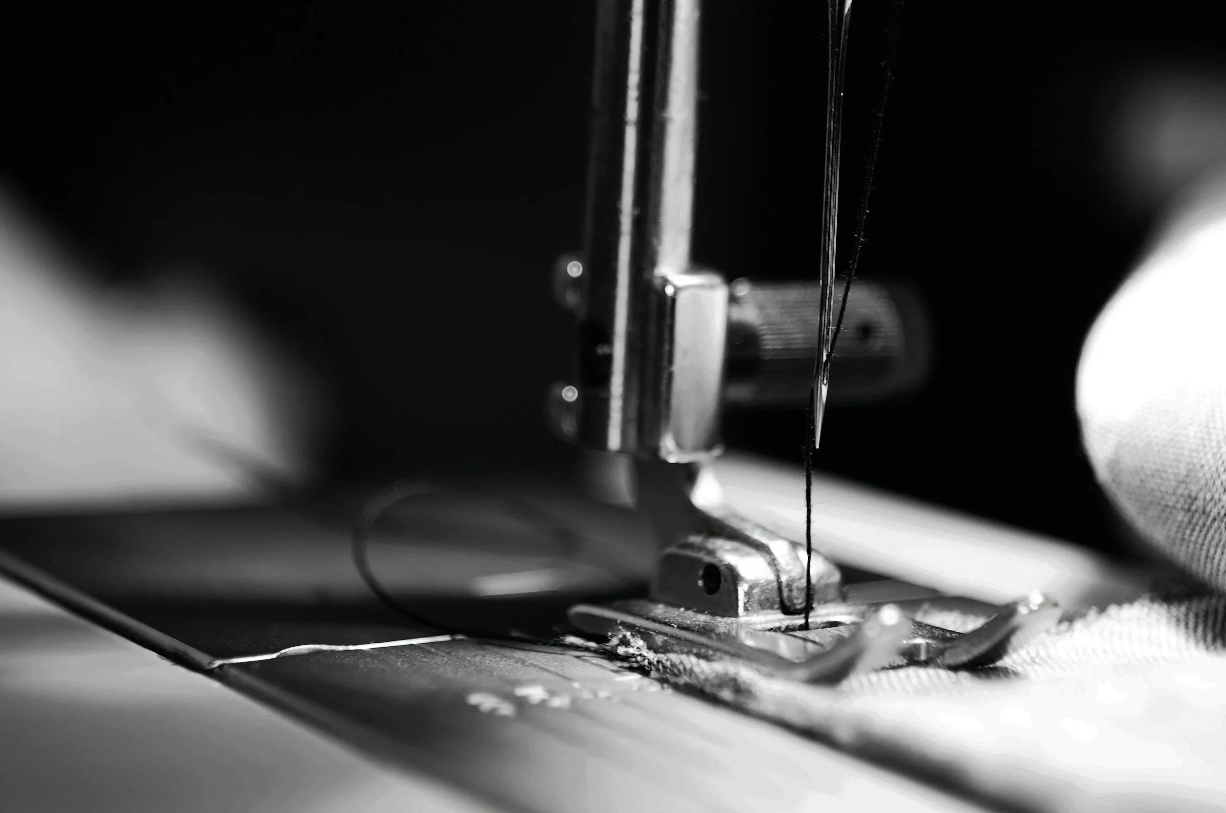 Close-up of a sewing machine needle sewing fabric.