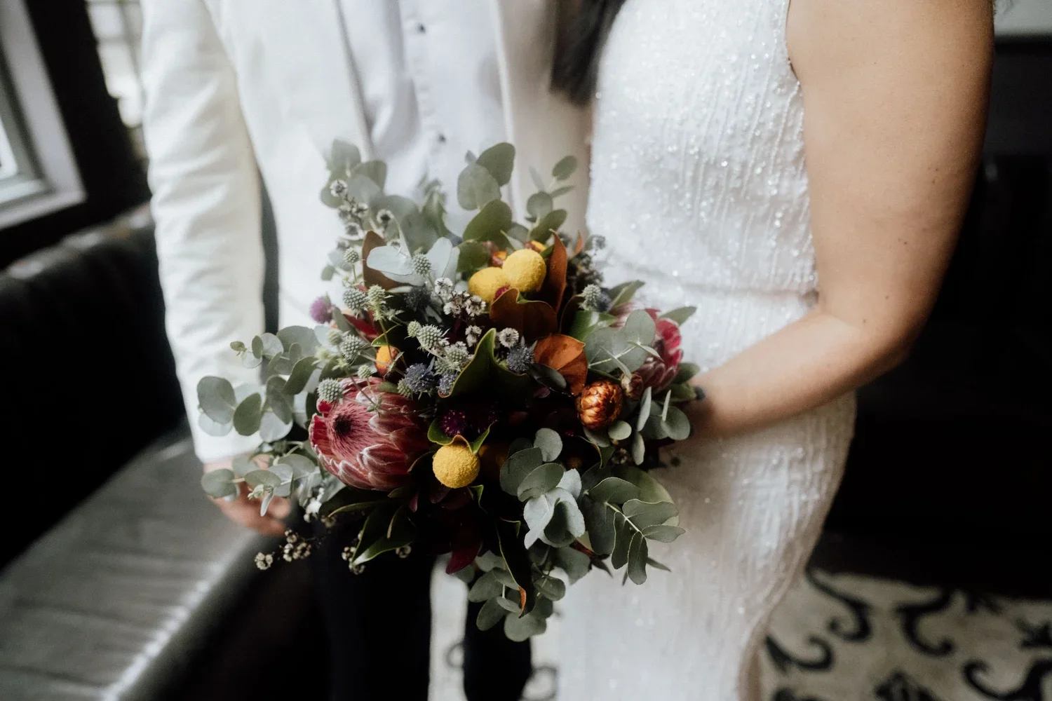 A woman in a white wedding dress holding a bouquet of flowers.