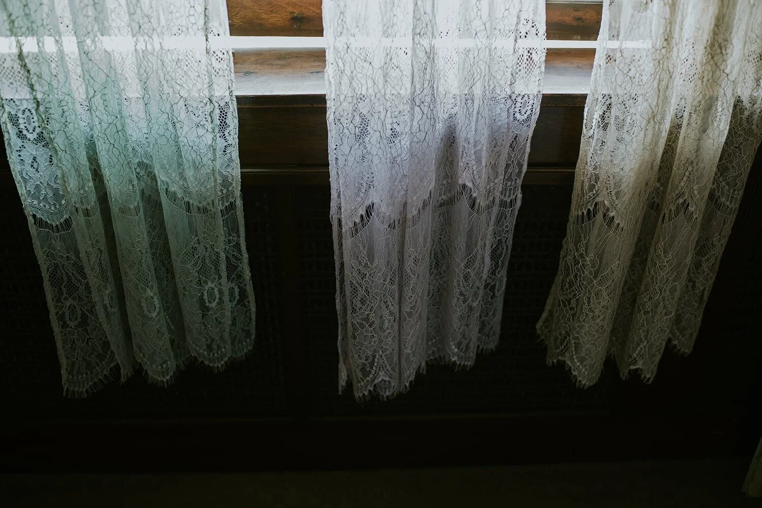 Close-up of lace curtains hanging in front of a window with a wooden frame