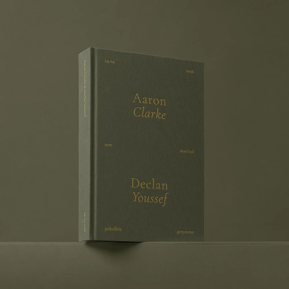 A dark green hardcover book standing upright on a surface with a plain olive-green background. The cover features gold text with the names Aaron Clarke and Declan Youssef, along with other smaller text.