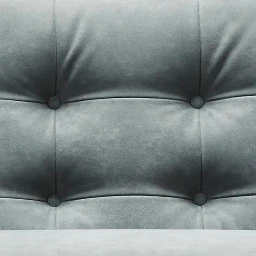 Close-up of a gray upholstered chair with tufted buttons.