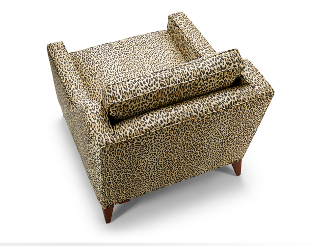 Leopard print armchair with wooden legs and a matching bolster cushion, viewed from above against a white background.