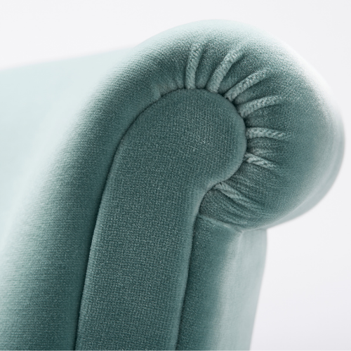 Close-up of a light blue upholstered armchair with rounded armrest and gathered fabric detail