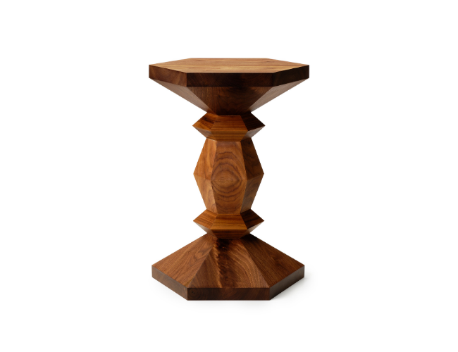 A wooden pedestal table with a geometric, faceted design and a hexagonal top.