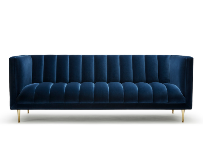 A navy blue velvet sofa with gold legs against a white background.