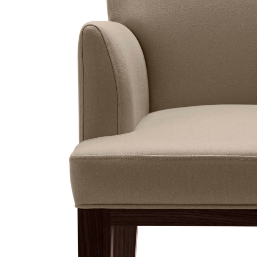 Close-up of a beige upholstered armchair with wooden legs.