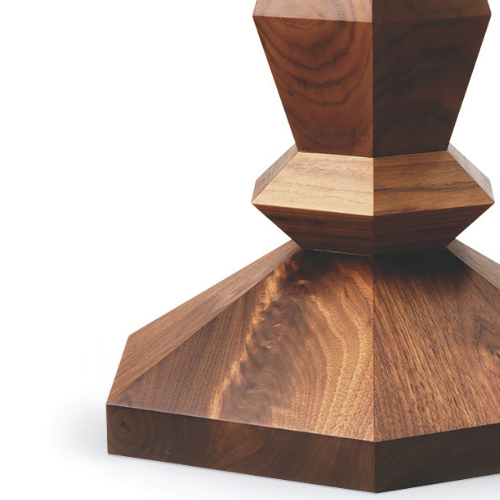 Close-up of a wooden sculpture with geometric shapes and a polished finish against a white background.