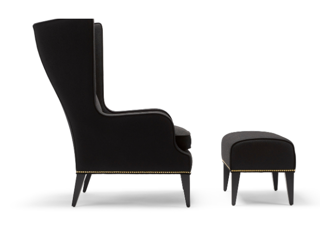 A black high-back armchair with a matching ottoman, both featuring gold nailhead trim, against a plain white background.