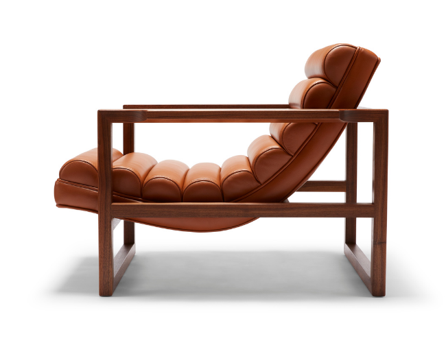 The Florence Easy Chair is a bare-wood constructed chair with a fluted leather seat in a light tan. Shown here from the low side