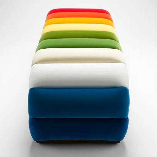 Stack of colorful upholstered chairs arranged from red at the top to dark blue at the bottom on a white background.