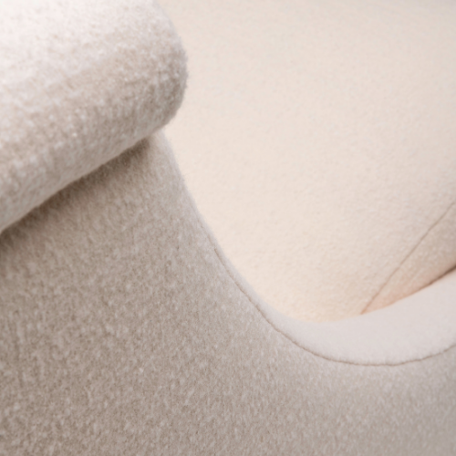 Close-up of a beige textured fabric armrest on a cream-colored upholstered chair.
