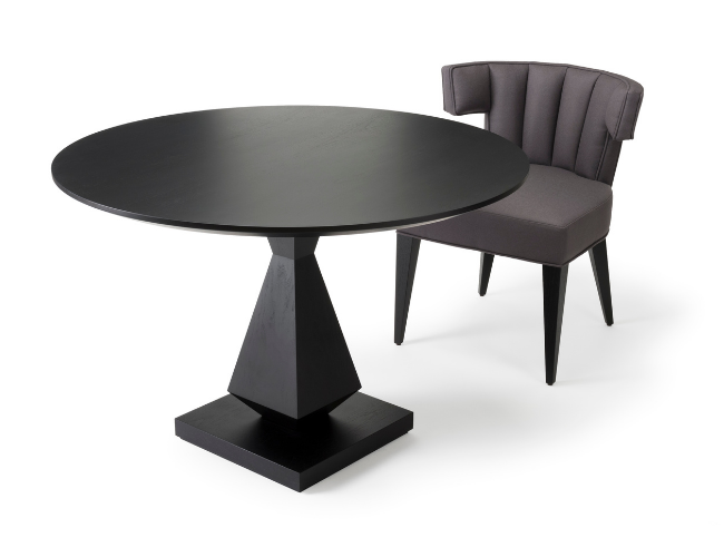 Black round dining table with a pedestal base and a gray upholstered chair with a curved back and tapered legs.