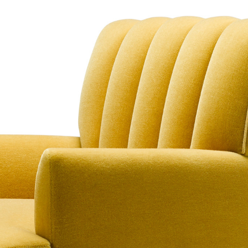 Close-up of a yellow upholstered vintage sofa with a rounded backrest and armrest.