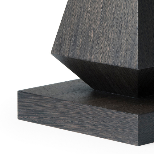 Close-up of a dark wooden geometric sculpture with a rectangular base and a polyhedral top.