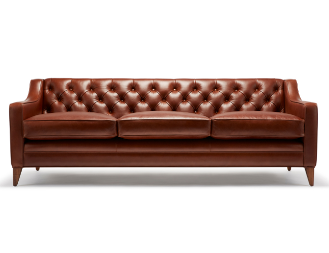 A brown leather tufted sofa with wooden legs on a white background.