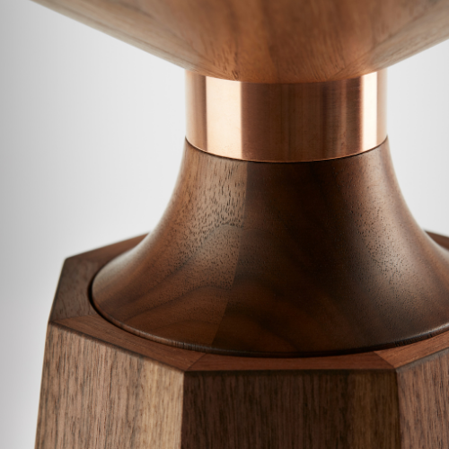 Close-up of a wooden table or stool with a metal accent at the base, showcasing the wood grain and craftsmanship.