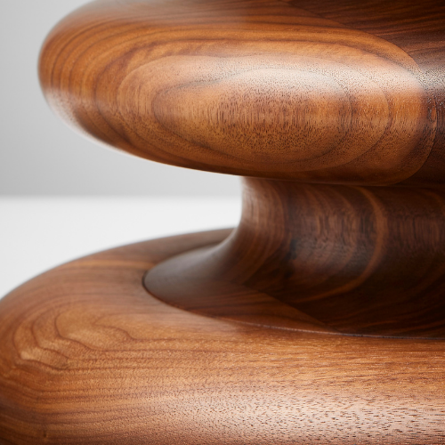 Close-up of a wooden sculpture showing smooth, rounded, layered surfaces with a natural wood grain finish.